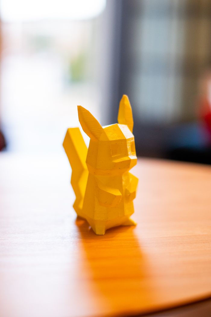 A yellow polygonal toy figurine resembling a popular character, placed on a wooden table indoors.
